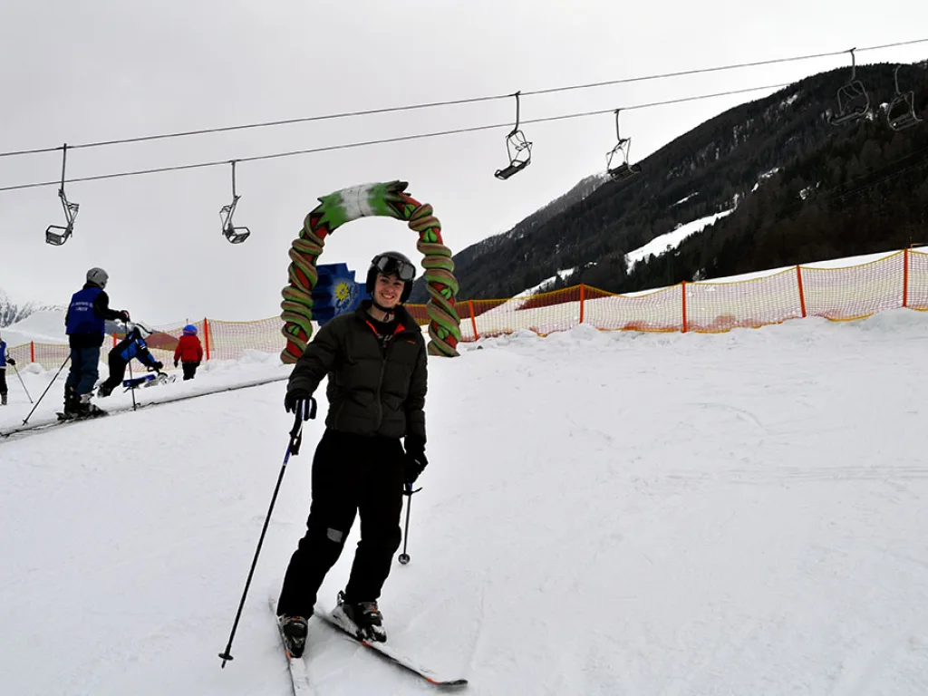 Skifahrer mit Siegerkranz um die Schultern steht auf der Piste.
